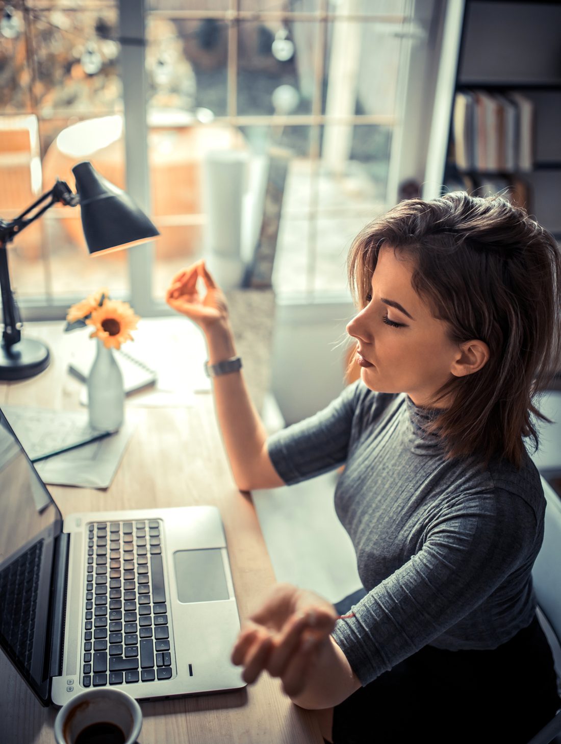 Person meditating in front of a laptop.